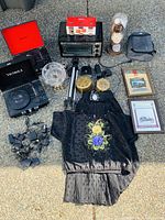 Overview photo showing most items including turntables, toaster oven, clocks, clothing, framed prints, tripod, crystal bowl, and string of lights