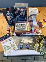 Overview photo showing the full grouping of movie and TV collectibles including stickers, action figures, boxed items, and retro toys on a wooden table.