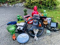 Full view of mixed collectibles on ground including models, glassware, bobblehead, and various figurines for lot overview.