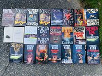 Photo showing a group of 24 Stephen King hardcover books laid out on the ground, displaying the cover art and titles.