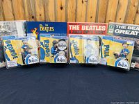 Group shot of all four sealed Beatles Spawn action figures with vinyl record sleeves in background.