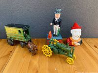 Overview of the four vintage cast iron items on a wooden surface against gray wall.
