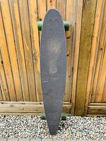 Top view of wooden longboard with black grip tape, showing wear in center.