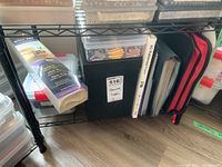 Overview of plastic storage containers and binders labeled for beads, appliques, and stencils on a black metal shelf