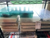 Three shelves of plastic organizers filled with labeled containers of beads