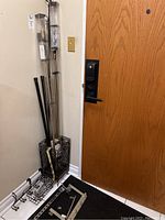 Metal umbrella stand, curtain rods, metal rods and hangers arranged by door corner