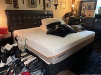 Tempur-Pedic mattress on foundation with headboard and assorted pillows