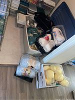 Bulk yarn skeins in various colors including yellow, white, cream, stored loosely in bins and containers on the floor.