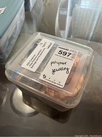 Clear plastic organizer box containing FED Creations polymer clay jewelry sets with label identifying contents.