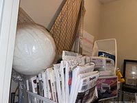 Stack of assorted clothing sewing patterns from McCall's, Butterick, and Simplicity packed standing upright in a container, including large floral netting and measurement rulers behind.