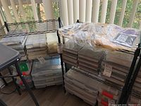 Two black metal wire grid utility shelves near a window with translucent blinds. Shelves have no contents included.