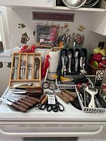 Overview of entire lot with various kitchen utensils, knives, forks, spoons, and liners on countertop.