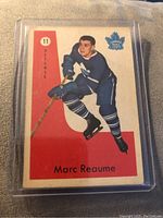 Front view of 1959-60 Parkhurst hockey card showing Marc Reaume in Toronto Maple Leafs uniform with red and white background and team logo.
