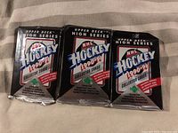 Three unopened 1990-91 Upper Deck High Series NHL Hockey Wax Packs placed side by side.