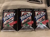 Three unopened wax packs of 1990-91 Upper Deck High Series hockey collector cards in original foil packaging.