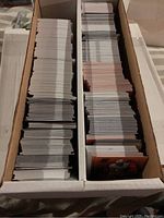 Two long cardboard trays filled with stacks of football and basketball trading cards, showing the thickness and quantity of the lot.
