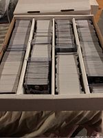Photo showing large box divided into multiple sections filled with stacks of hockey trading cards.