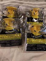 Four yellow disposable yellowjacket traps sealed in clear packaging with black grid and yellowjackets illustrated on the bag.