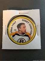 Front side of Gerry Cheevers collectible coin showing player portrait in Boston Bruins uniform and season years.