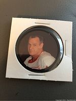 Front side of the Gordie Howe hockey coin displaying colored image of Gordie Howe in jersey inside white cardboard holder with clear plastic window.