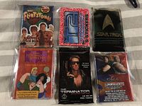 Photo of six unopened non-sport wax trading card packs arranged in two rows of three on a fabric surface.