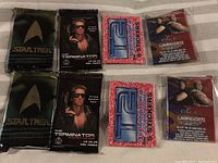 8 wax packs including 2 Star Trek, 2 The Terminator, 2 red and blue Technotoys sticker packs, and 2 WWE collectible packs.