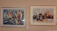Two framed abstract sailboat paintings side by side on a wall.