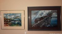 Both framed artworks hung on wall, showing left abstract painting and right locomotive print