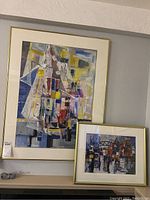 Two framed abstract paintings by Pablo Schoenefuhs, displayed together. Larger painting with ship and smaller with bridge scene.