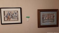 Both framed artworks hung on a wall with visible signatures and sailboat imagery.