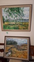 Two framed original landscape paintings by Pablo Schoenefuhs hung one above the other, showing birch trees and a marshy landscape.