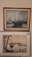 Two framed original paintings hanging on wall, one depicting a large sailboat and the other a boat dock scene with mountains