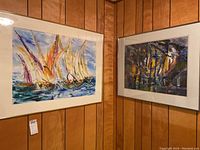 Two framed paintings by Pablo Schoenefuhs displayed side by side on a wood panel wall.