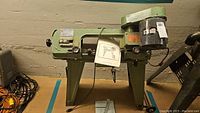Full view of green metal cutting band saw on stand with manual suspended