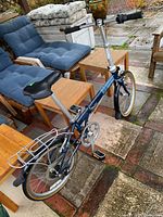 Full view of Dahon collapsible bicycle with blue frame and silver handlebar and seat post, showing rear rack and folded chain guard.