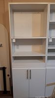White tall cabinet with two open shelves and two-door cabinet below. Shows full front view for size and design.