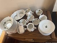 Top view of bowls, cups, saucers, and serving dish showing green leaf motif on white ironstone with latticed rims.
