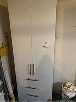 Full view of the white composite board cupboard with two doors and three drawers.