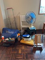 Full lot overview including fan, step stool, shopping cart, first aid blankets, and assorted health aid items