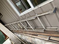 Full view of the 28ft aluminum extension ladder leaning against an exterior wall, showing length and condition.