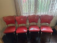Four red vinyl retro chairs with metal frames and curved backrests, arranged in a row.