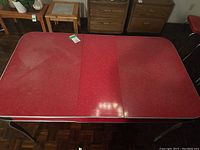 Full view of retro rectangular table with red melamine top and central leaf section, metal legs visible.