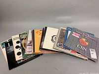 Photo showing a stack of various vintage vinyl record albums from different artists with visible spine and cover art.