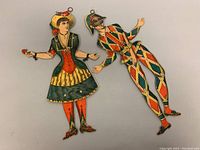 Full view of both marionette cardboard cutouts showing the female and male figures connected with jointed limbs and hanging rings.