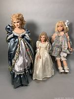 Front view of all three dolls standing side-by-side showing varied clothing and sizes.