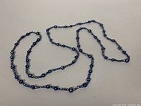 Full view of the 60-inch lariat necklace with dark baroque and round beads laid out on a flat surface.