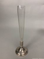 Tall slender glass bud vase with sterling silver frame and silver plated base, showing some rim dents