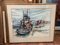 Framed artwork showing a dock scene with boats, dominated by a red-black tugboat named 'Traveller' in the foreground. The frame shows some wear and tear.