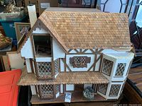 Front view of handcrafted Tudor-style doll house showing detailed shingle roof, bay windows, and flower boxes.
