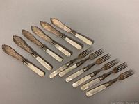 Full set of 6 fish forks and 6 fish knives with mother of pearl handles and etched metal blades and fork tines.